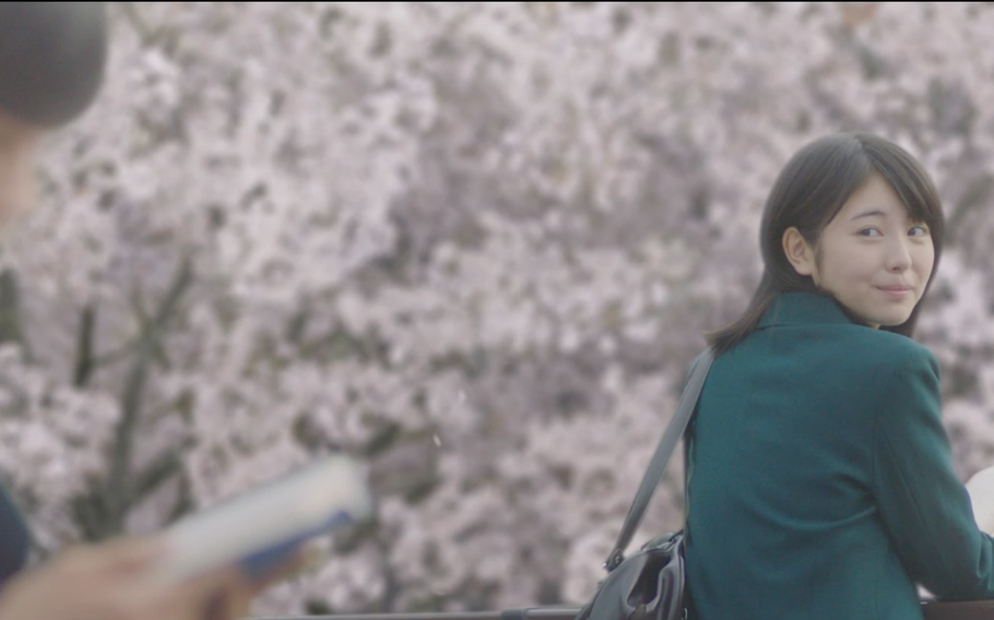 A high school girl with a book looks back in order to see a high school boy who is reading in the movie “ I Want to Eat Your Pancreas”.